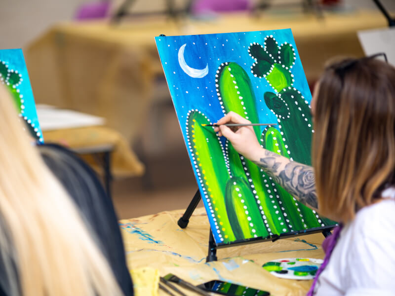 A person learns how to paint a colourful cactus artwork.